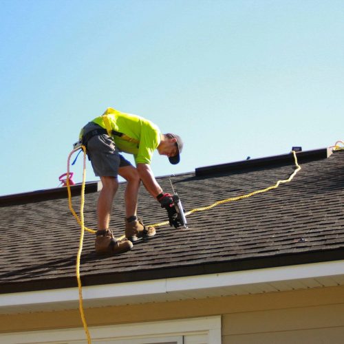 a man working on a roof with a power drill